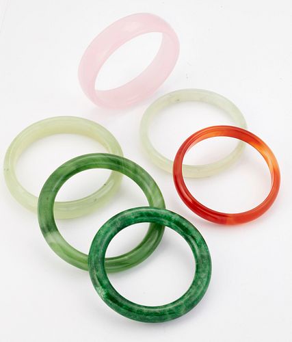 A GROUP OF FIVE JADE AND OTHER HARDSTONE BANGLES AND A GREEN GLASS BANGLE. 