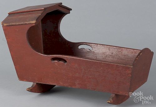 Painted pine doll cradle, 19th c., retaining an old red surface, 11'' h., 18'' w.
