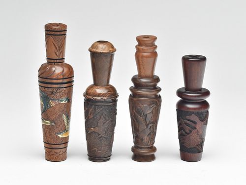 Four heavily carved duck calls by different makers.