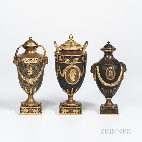 Three Wedgwood Gilded and Bronzed Black Basalt Vases with Covers, England, c. 1885, one with zodiac band above oval classical medallions bordered by f