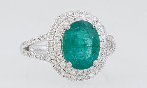 Lady's Platinum Dinner Ring, with an oval 2.5 ct. emerald, atop a conforming border of round diamonds, the split shoulders of the band also mounted wi