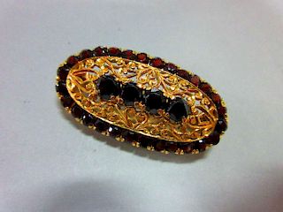 An Italian 18ct gold and garnet brooch, of elongated oval outline delineated by round cut deep red g