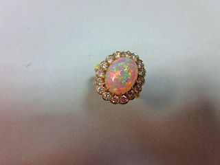 An opal and diamond cluster ring, the oval cabochon opal, displaying a rainbow range of fire, claw s