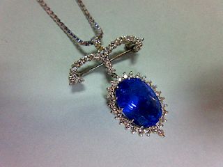 A sapphire and diamond pendant / brooch with white gold chain, the jewel designed as a large oval cu