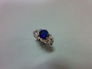 A sapphire and diamond ring, the round cut royal blue sapphire between shoulders with curved bands s