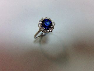 A sapphire and diamond cluster ring, the round cut sapphire in a border of old variously round cut d