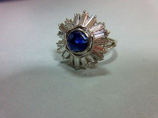 A sapphire and diamond sunburst cluster ring, the round cut light indigo coloured sapphire collet se