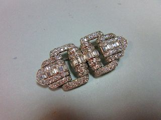 A French art deco odeonesque diamond and platinum brooch, of pierced double buckle form, with a cent