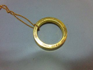 A Tiffany gold ring pendant and chain, the solid ring, diameter 2.6cm, with concave edge, and engrav
