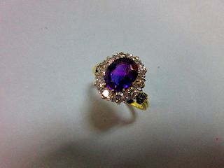 An amethyst and diamond cluster ring, the oval mixed cut rich purple amethyst claw set in a border o