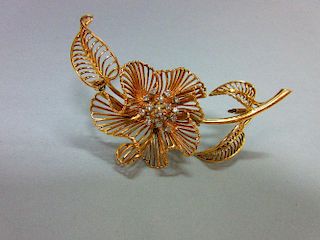 A mid-20th century diamond set flower brooch, of open wirework structure with three curled leaves an