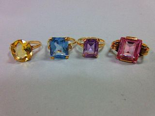 A collection of four single gem stone rings, variously a pale blue spinel, an amethyst and a synthet