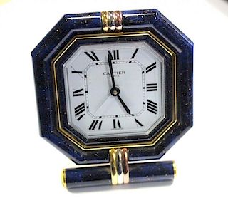 By Cartier - a brass cased travel alarm clock, with blue enamel and three tone gold plated octagonal