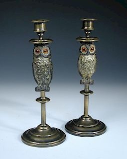 A pair of late 19th century brass candlesticks, the columnular stems set with a figure of a cold pai