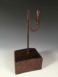An 18th century iron rushlight holder with later wooden base, the square stem topped by a squared ja
