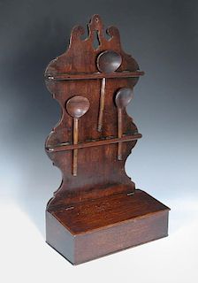 An 18th century oak spoon rack, the shaped back fitted with two pierced spoon rails above a hinged b