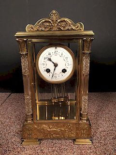 A French gilt brass four-glass mantle clock, with swagged enamel 8cm (3in) dial, glass front corner