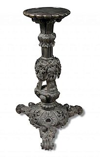 An early 19th century Indian ebony pedestal, profusely carved with leaves, flowers and figure heads,