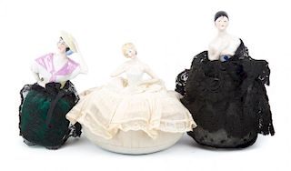 Three porcelain and cloth doll pin cushions