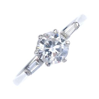 An 18ct gold diamond single-stone ring. The brilliant-cut diamond, to the tapered baguette-cut diamo