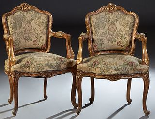 Pair of Louis XV Style Carved Giltwood Fauteuils, 20th c., the arched floral carved curved upholstered back to upholstered arms and a bowed upholstere