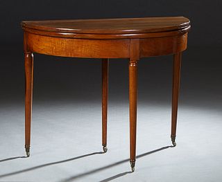 French Louis Philippe Carved Walnut Demilune Games Table, 19th c., the demilune top over a wide skirt, on turned tapered cylindrical legs with toupie 
