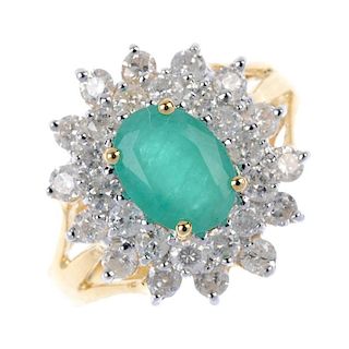 An 18ct gold emerald and diamond cluster ring. The oval-shape emerald, within a brilliant-cut diamon