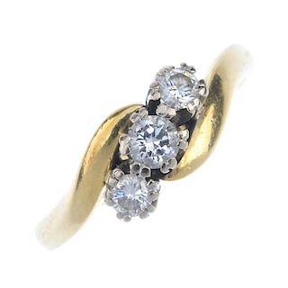 An 18ct gold diamond three-stone ring. The graduated brilliant-cut diamond diagonal line, to the asy