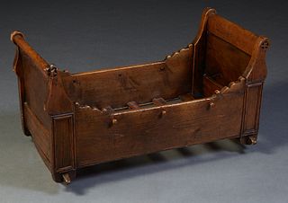 French Provincial Louis Philippe Style Carved Pine and Oak Cradle, 19th c., with a star carved head and footboard, joined by shaped wooden rails, on r