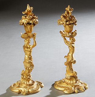 Pair of Continental Gilt Bronze Figural Candlesticks, 19th c., the nude female upholding a shell form bobeche with a floriform candle cup with a fruit