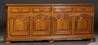 French Provincial Carved Oak Sideboard, early 20th c., the stepped rounded edge and corner top over four frieze drawers above four fielded panel cupbo