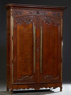 French Provincial Louis XV Style Carved Walnut Armoire, early 19th c., the stepped canted corner crown over a relief carved frieze above two long fiel