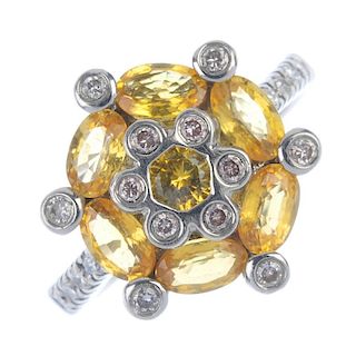 A sapphire and diamond cluster ring. The circular-shape yellow sapphire, within an oval-shape yellow