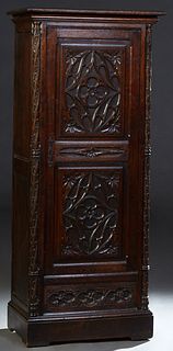 French Provincial Henri II Style Carved Oak Bonnetiere, c. 1880, the stepped crown over a long single door cupboard with Gothic relief carving, flanke