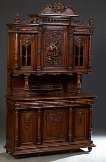 French Provincial Carved Walnut Buffet a Deux Corps, late 19th c., the broken arch crest over a stepped crown above a setback figural carved center cu
