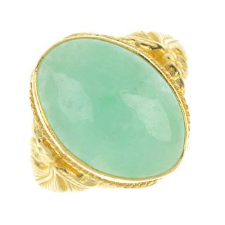 A jade ring. The oval jade cabochon collet, with floral embossed motif shoulders and plain band. Wei