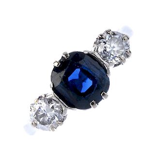 A mid 20th century platinum and 18ct gold sapphire and diamond three-stone ring. The oval-shape sapp