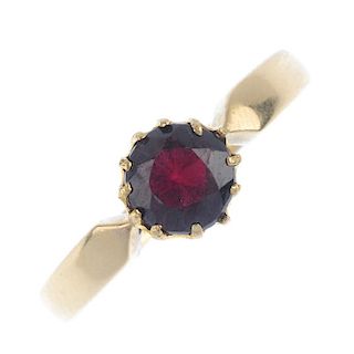 An early 20th century 18ct gold garnet single-stone ring. The circular-shape garnet, to the tapered