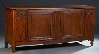 French Provincial Louis XV Style Carved Oak Sideboard, 19th c., the two board top with a rear plate groove, over double cupboard doors flanking a reed