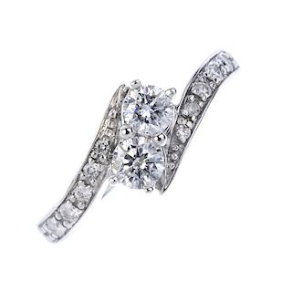 A diamond two-stone crossover ring. The brilliant-cut diamond, to the similarly-cut diamond crossove