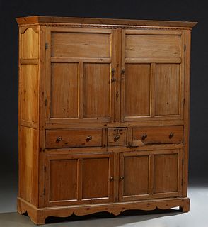 Continental Pine Cupboard, 19th c., the sloping crown over a scalloped molding above double wide cupboard doors, over a center deep drawer flanked by 