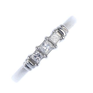 An 18ct gold diamond three-stone ring. The graduated square-shape diamond line, to the polished bar