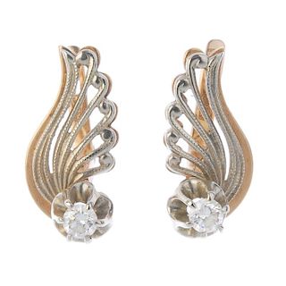 A pair of diamond earrings. Each designed as a brilliant-cut diamond, to the stylised scrolling wing