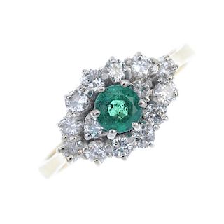 An 18ct gold emerald and diamond cluster ring. The circular-shape emerald, with brilliant-cut diamon