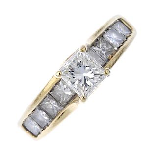 A diamond single-stone ring. The square-shape diamond, set atop a similarly-cut diamond line, to the