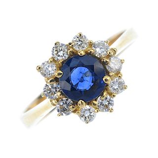 A sapphire and diamond cluster ring. The circular-shape sapphire, within a brilliant-cut diamond sur