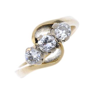 A diamond three-stone ring. The brilliant-cut diamond line, to the asymmetric sides and plain band.
