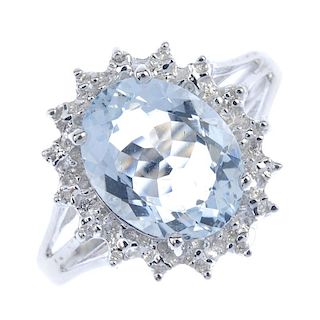 A 9ct gold aquamarine and diamond cluster ring. The oval-shape aquamarine, within a illusion-set dia