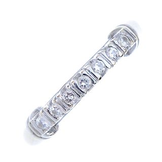 A diamond dress ring. The brilliant-cut diamond line, raised to the grooved bar sides and plain band