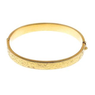 A 1930s 9ct gold hinged bangle. With scrolling foliate engraved front and polished reverse. Hallmark